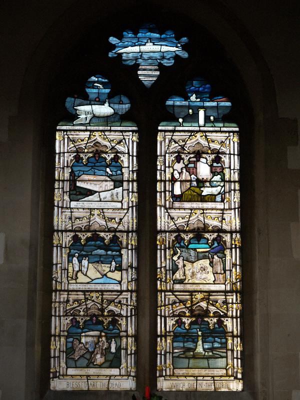 Swaffham Prior, England: St Mary's Church: Great War (World War I) middle memorial window (scenes from bottom left: motor field kitchen with Red Cross workers; pipe line for water laid across Sinatic peninsular during invasion of Palestine; YMCA hut; German submarine mine layer;  British submarine; sinking of Lusitania, with mines on floor of sea; Red Cross hospital in French house; military chaplain; Statue of Liberty) (1919, designed by T F Curtis, made by Ward and Hughes)