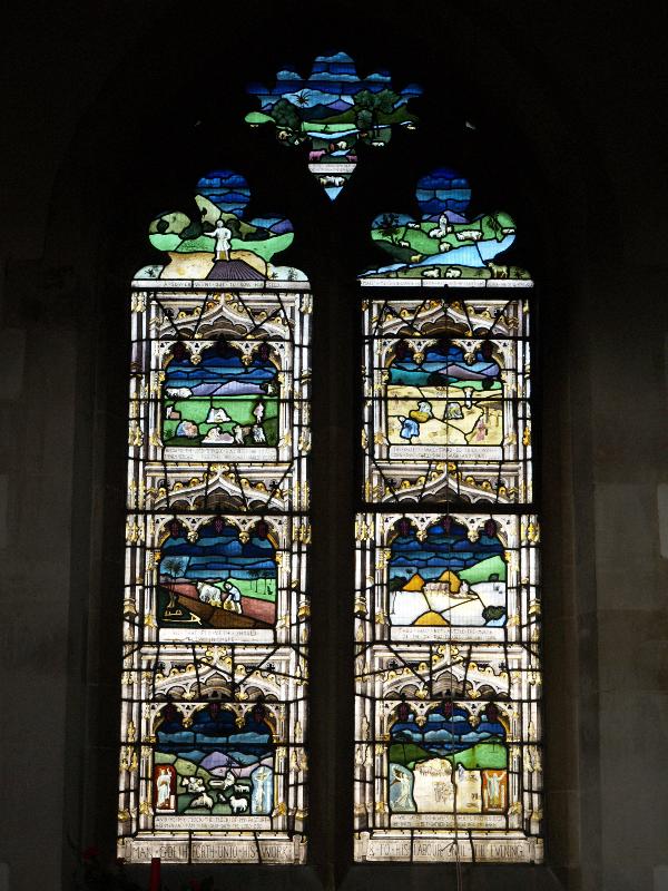 Swaffham Prior, England: St Mary's Church: Great War (World War I) right memorial window (scenes from bottom left: Christ the Good Shepherd; ploughing; various agricultural activities; parable of the sower; sheep, cattle and camels feeding; watering sheep; harvesting; threshing by oxen; harvest on earth and in heaven) (1919, designed by T F Curtis, made by Ward and Hughes)