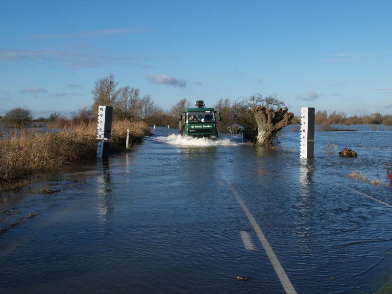 Welney, England: Wash Road (A1101): lorry (truck) driving along flooded road