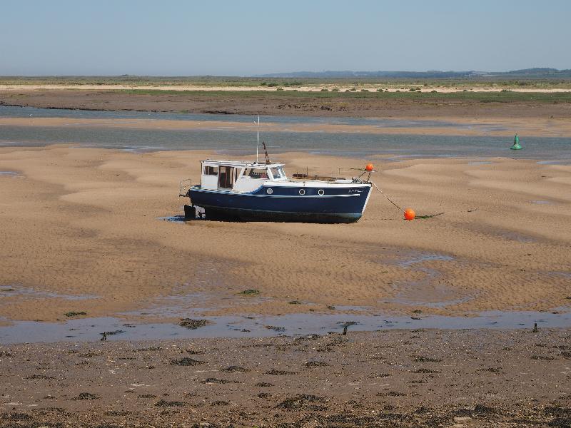 Wells-next-the-Sea, England: Beach Road: boat in inlet at low tide