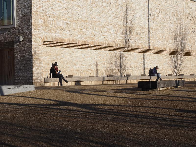Cambridge, England: Eddington, Storey's Field Centre: two people reading in winter sun