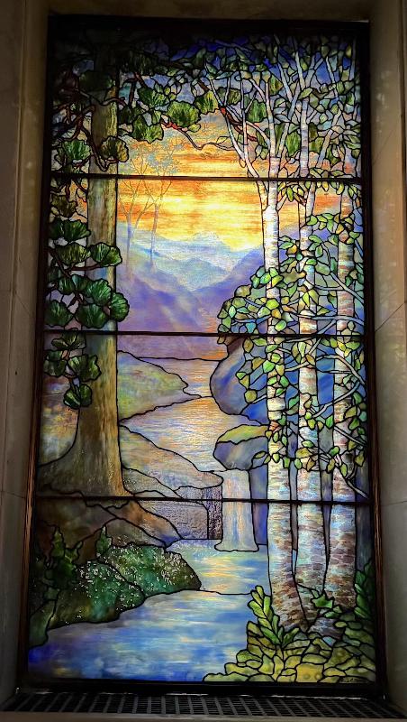Schram Memorial Window:  landscape with conifers at left, birch trees at right, mountains and water