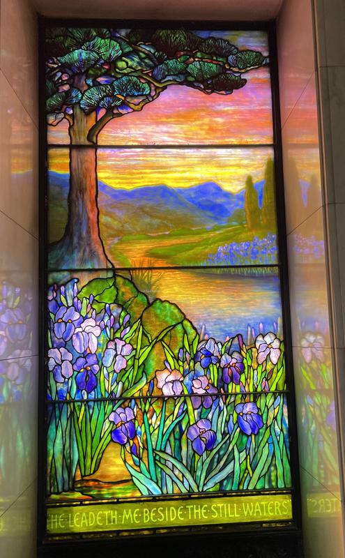 L.E. Block Memorial Window:  landscape with conifer at left, mountains, water and irises